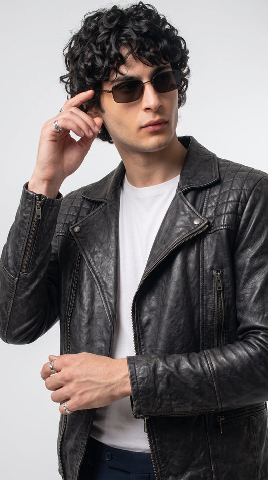 Black grained leather biker jacket showcasing diamond-quilted shoulders, snap-button lapels, polished silver zipper teeth and vertical zippered chest pockets, combining rugged motorcycle heritage with a refined contemporary designer aesthetic.