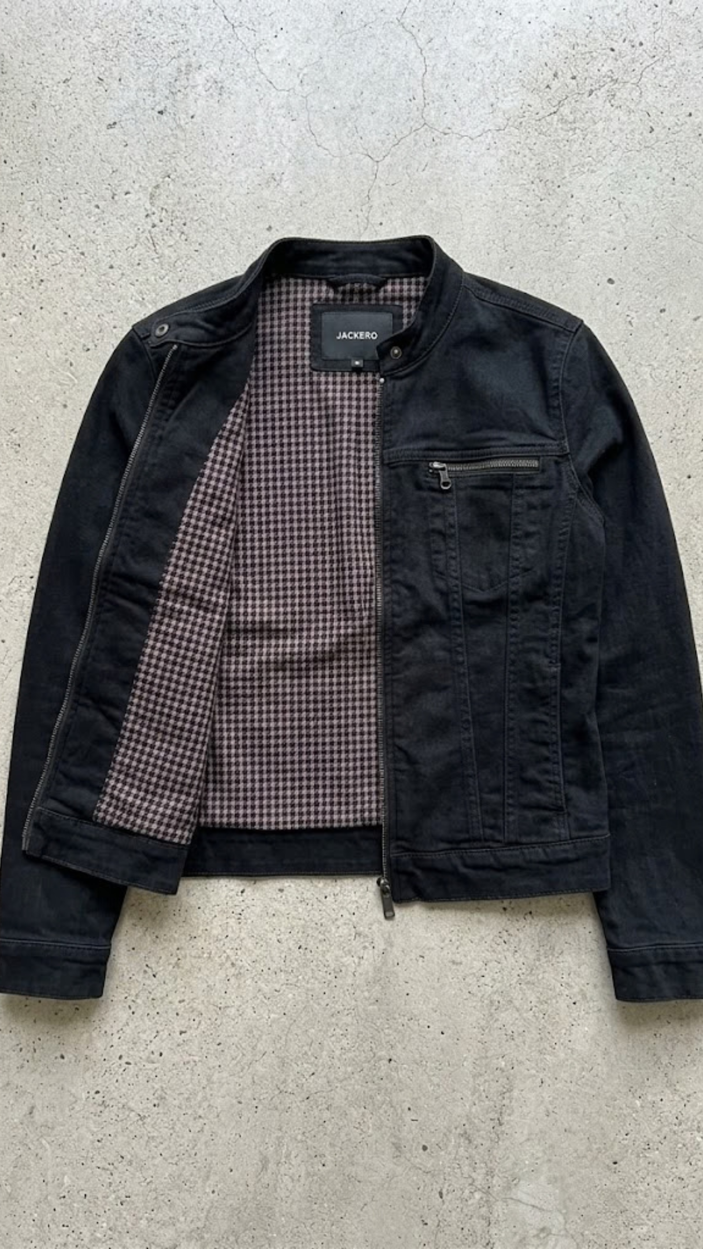 Flat lay professional photography of Jackero minimalist black denim jacket on a grey background