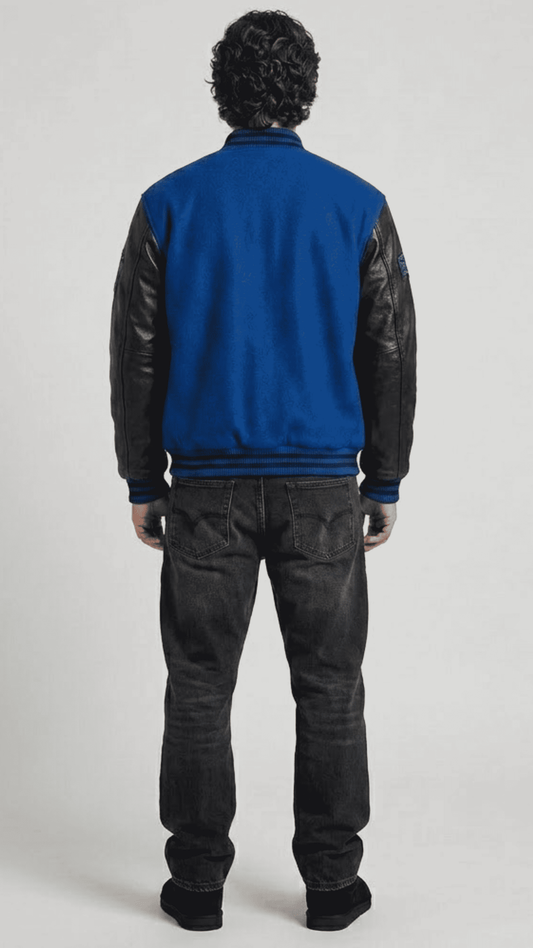 Detailed view of the athletic striped rib-knit collar, cuffs, and waistband on a premium blue suede varsity jacket.