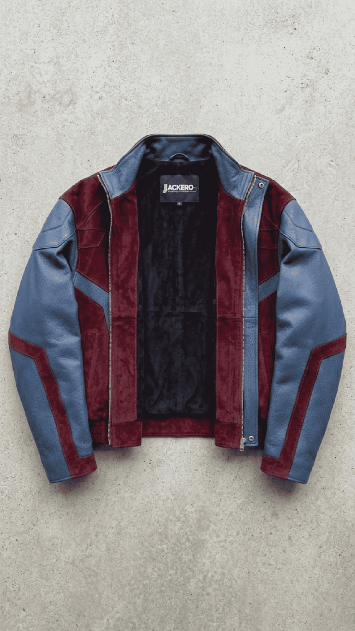 A color-blocked leather and suede jacket by Jackero, featuring blue leather sleeves and side panels, burgundy suede-like front and inner collar panels, and a black interior lining, laid flat on a textured gray concrete background.