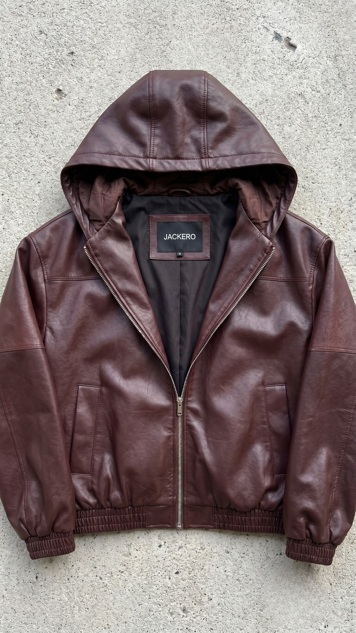 Detailed hardware close-up of a premium maroon hooded leather bomber showing high-grade brass metallic zippers and soft interior lining.
