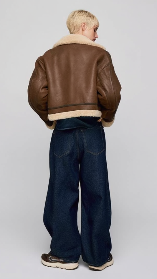 Women's stylish brown cropped aviator jacket with white shearling trim, styled for a modern winter streetwear look.