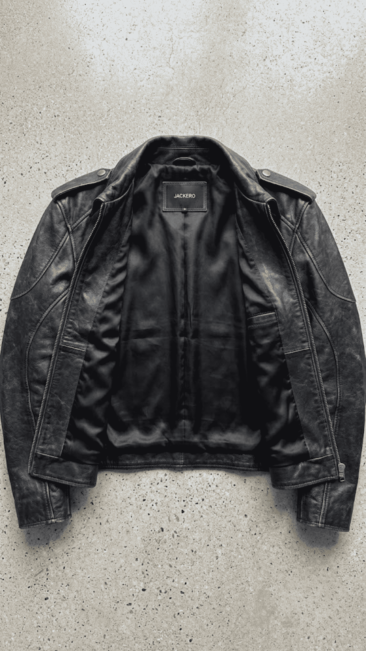 flat lay photography of a high-end vintage wash black leather café racer coat on a solid neutral backdrop.