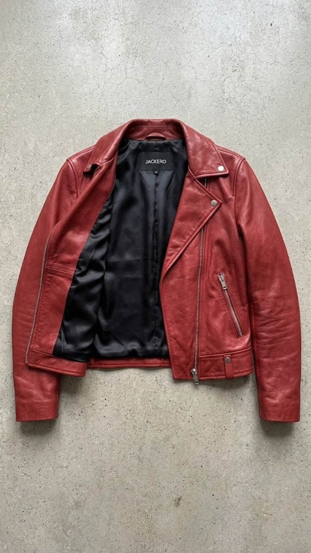 Jackero jacket flat lay photography of a high-end scarlet red leather motorcycle coat displayed on a solid grey backdrop.