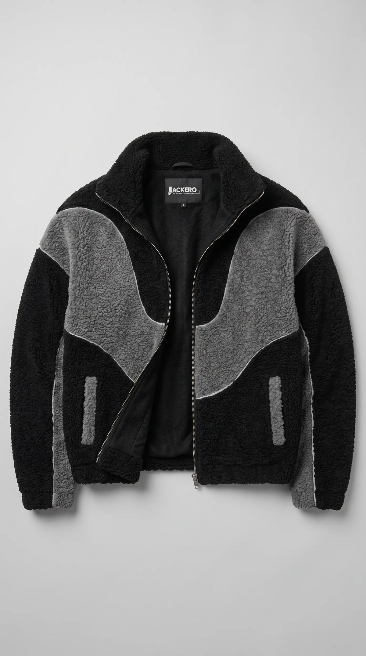 JACKERO black and dark grey Y2K jacket displayed open to reveal its smooth black inner lining, full-length metal zipper and high stand-up collar. The plush wool-blend fleece exterior features sculpted charcoal-grey panels, contrasting white piping and two side waist pocket openings, combining a distinctive oversized silhouette with functional everyday outerwear details.