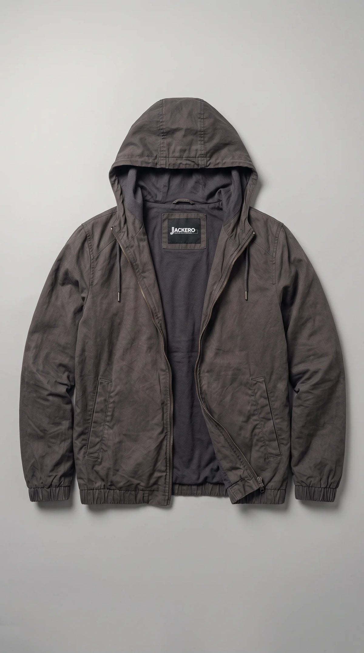 JACKERO dark-grey silk-cotton hooded jacket displayed open to reveal its smooth charcoal inner lining, branded neck label, full-length zipper and adjustable drawstring hood. The two discreet waist pockets, elasticated cuffs and matching hem complete its functional minimalist design, giving this contemporary casual jacket a clean finish for everyday layering and refined streetwear.