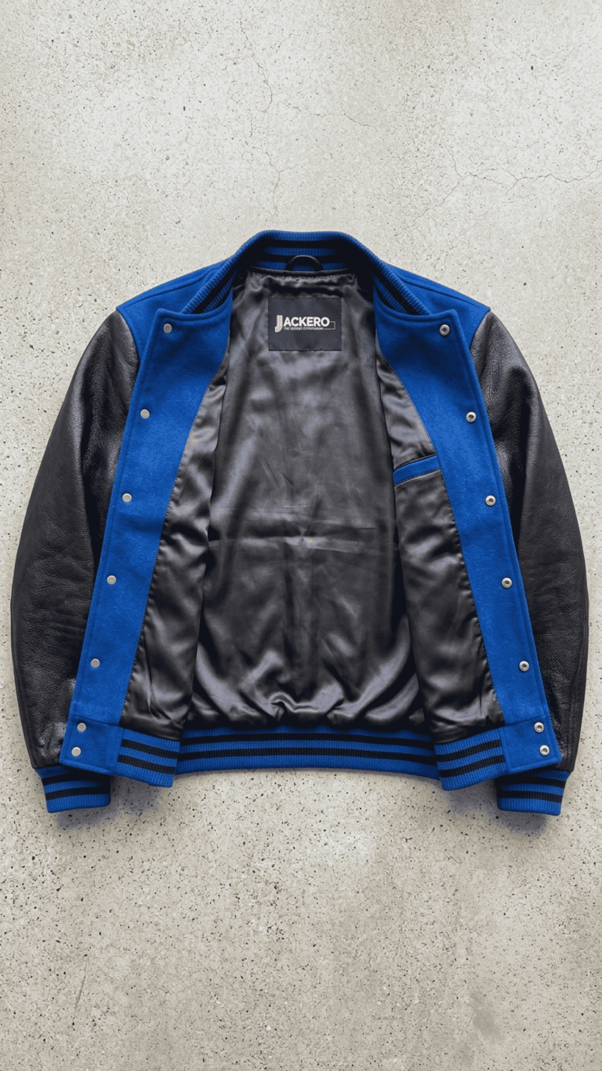 Jackero blue suede and black leather varsity jacket beautifully presented against a clean, minimalist studio backdrop.