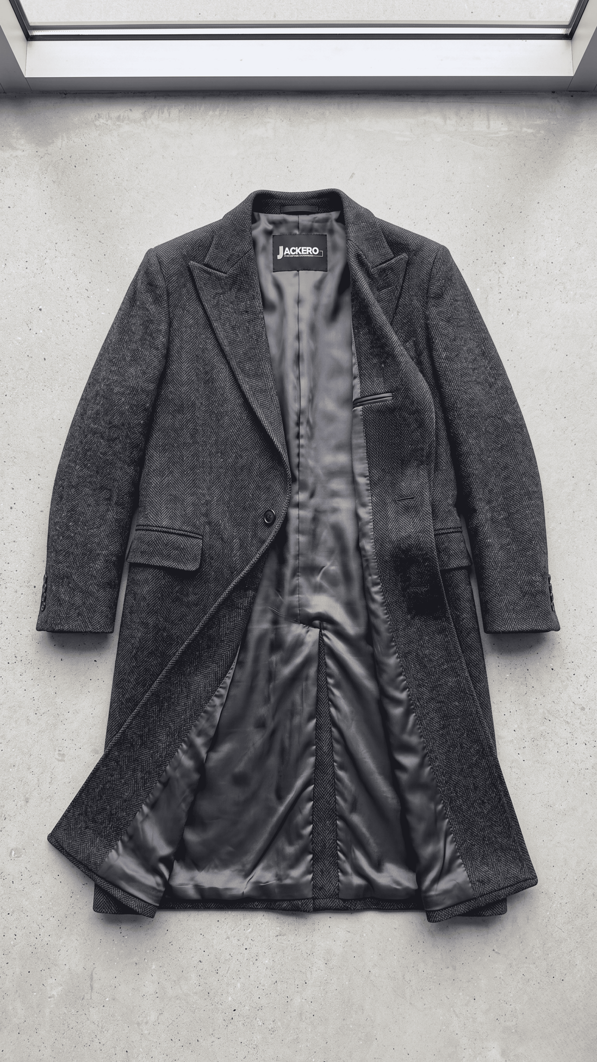 Jackero dark grey wool overcoat beautifully presented against a clean, minimalist studio backdrop.