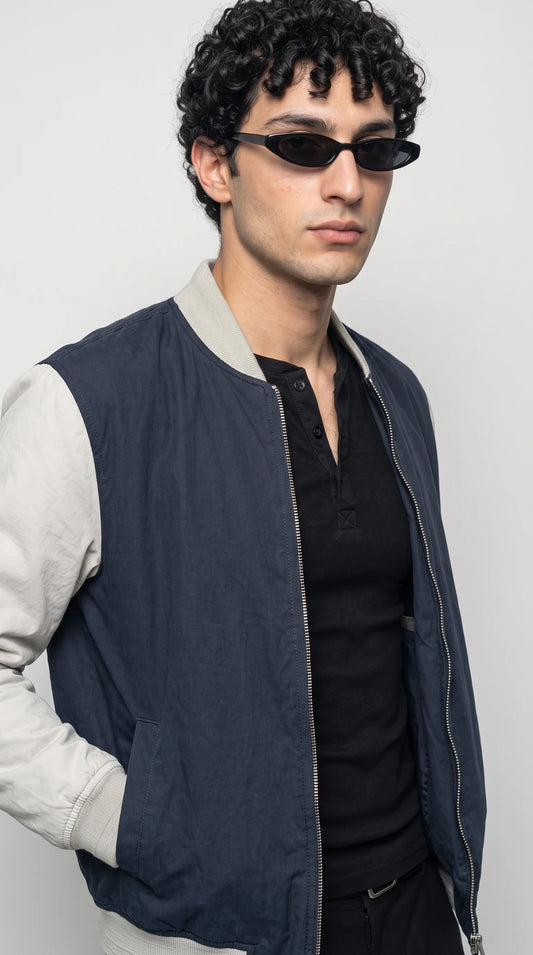 Dark navy cotton bomber jacket with a contrasting grey sleeve construction, compact rib-knit collar, sturdy metal front zipper and neatly finished shoulder seams, highlighting its understated two-tone design and versatile everyday outerwear appeal.
