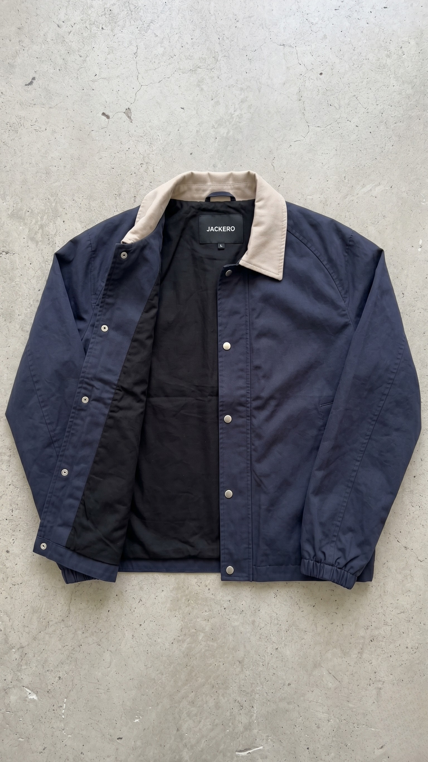 flat lay display featuring a neatly folded premium dark navy blue coach jacket for a clean online catalog layout.