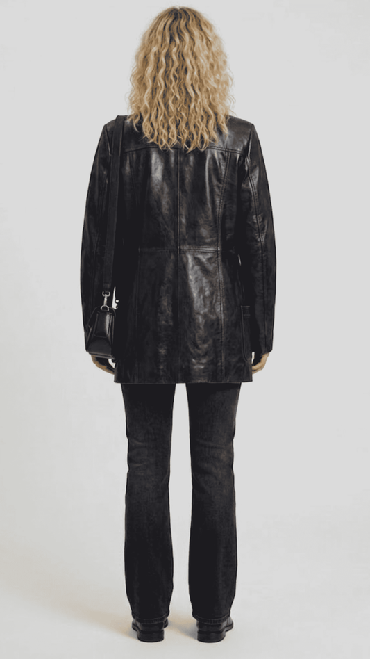 back-angle profile view of a regular fit black leather trench coat displaying smooth drape, neat hemline, and comfortable tailoring alignment.