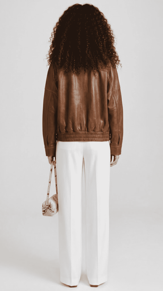 Minimalist studio portrait showcasing a women's oversized caramel brown lambskin leather coat.