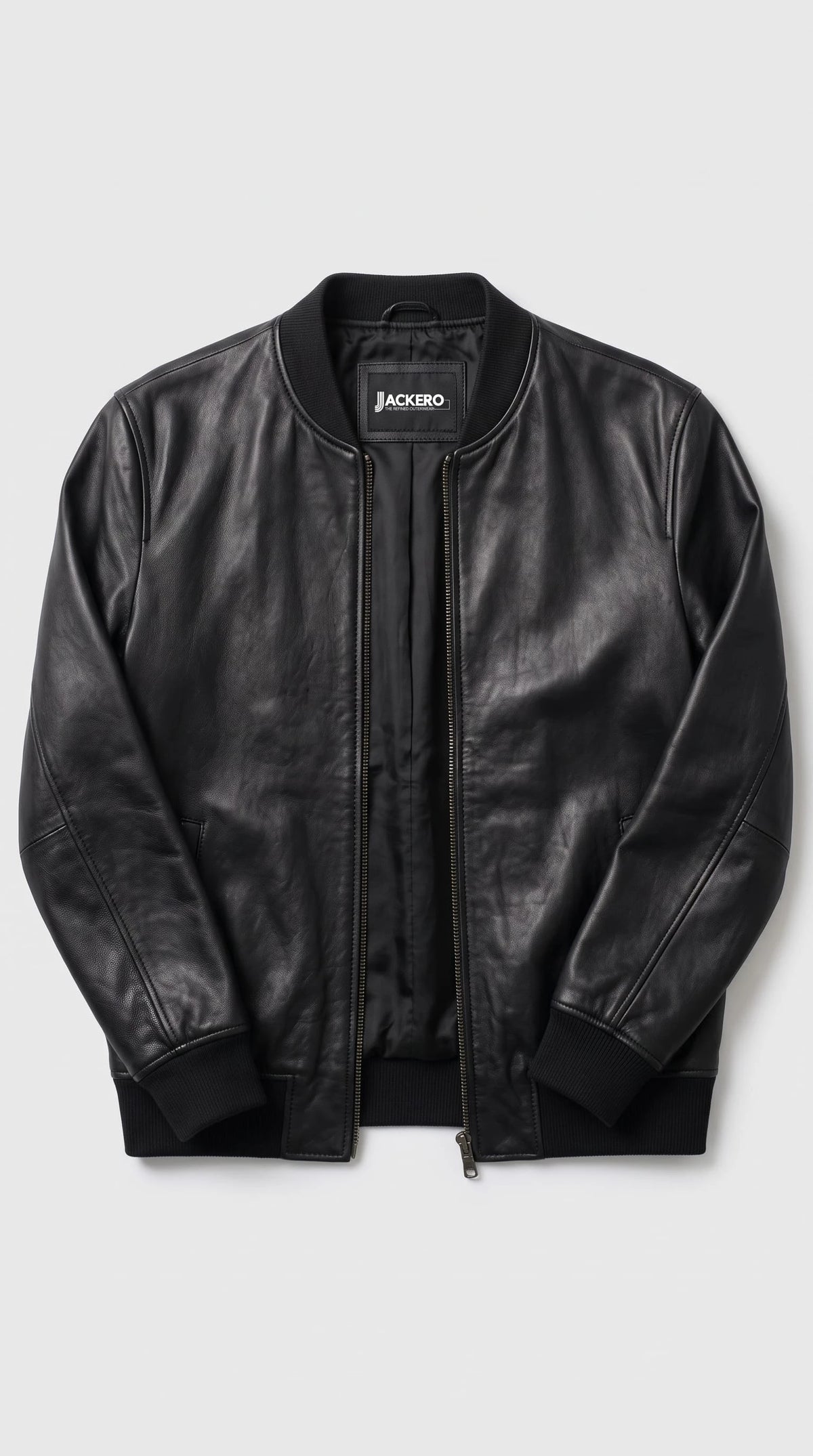 Detailed black genuine leather bomber craftsmanship highlighting the smooth-grain semi-matte surface, metallic zipper teeth, precise leather stitching and tonal rib-knit trim for a clean premium outerwear finish.