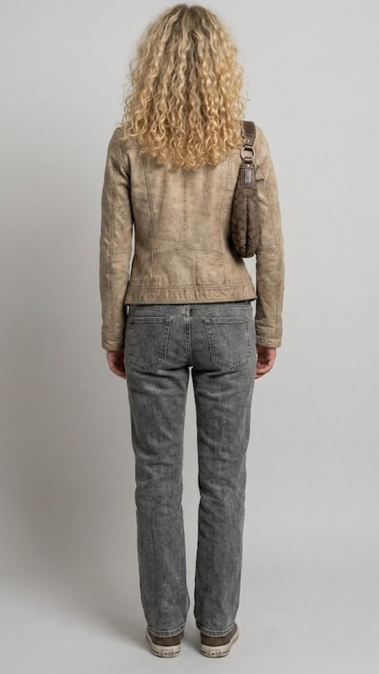 A model shown from the back wearing a cropped burgundy leather jacket with cream stripes on the shoulders and sleeves, paired with dark blue wide-leg jeans and white sneakers, against a solid gray background.