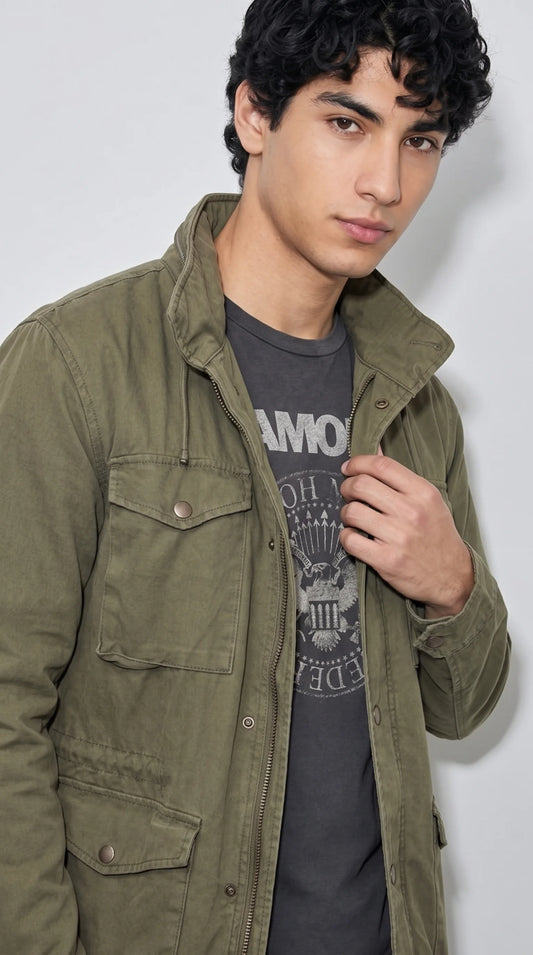 Close-up of an olive cotton-blend utility jacket highlighting its structured collar, metal front zipper beneath a snap-button placket, twin chest flap pockets and rugged textured fabric, combining practical fieldwear construction with a clean modern casual look.