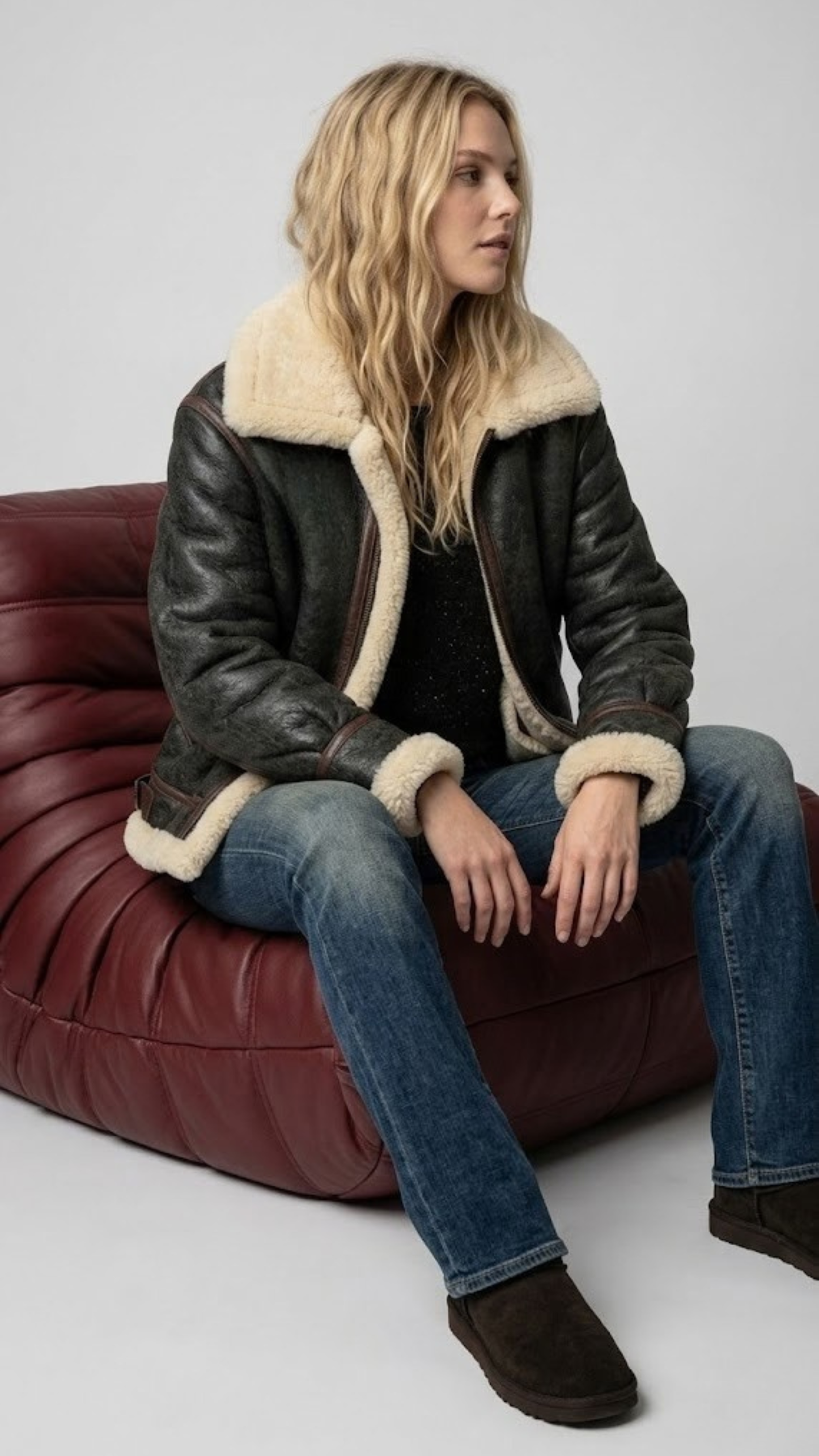 Clean studio photography of a men's luxury black genuine leather coat featuring a striking faux cream shearling trim.
