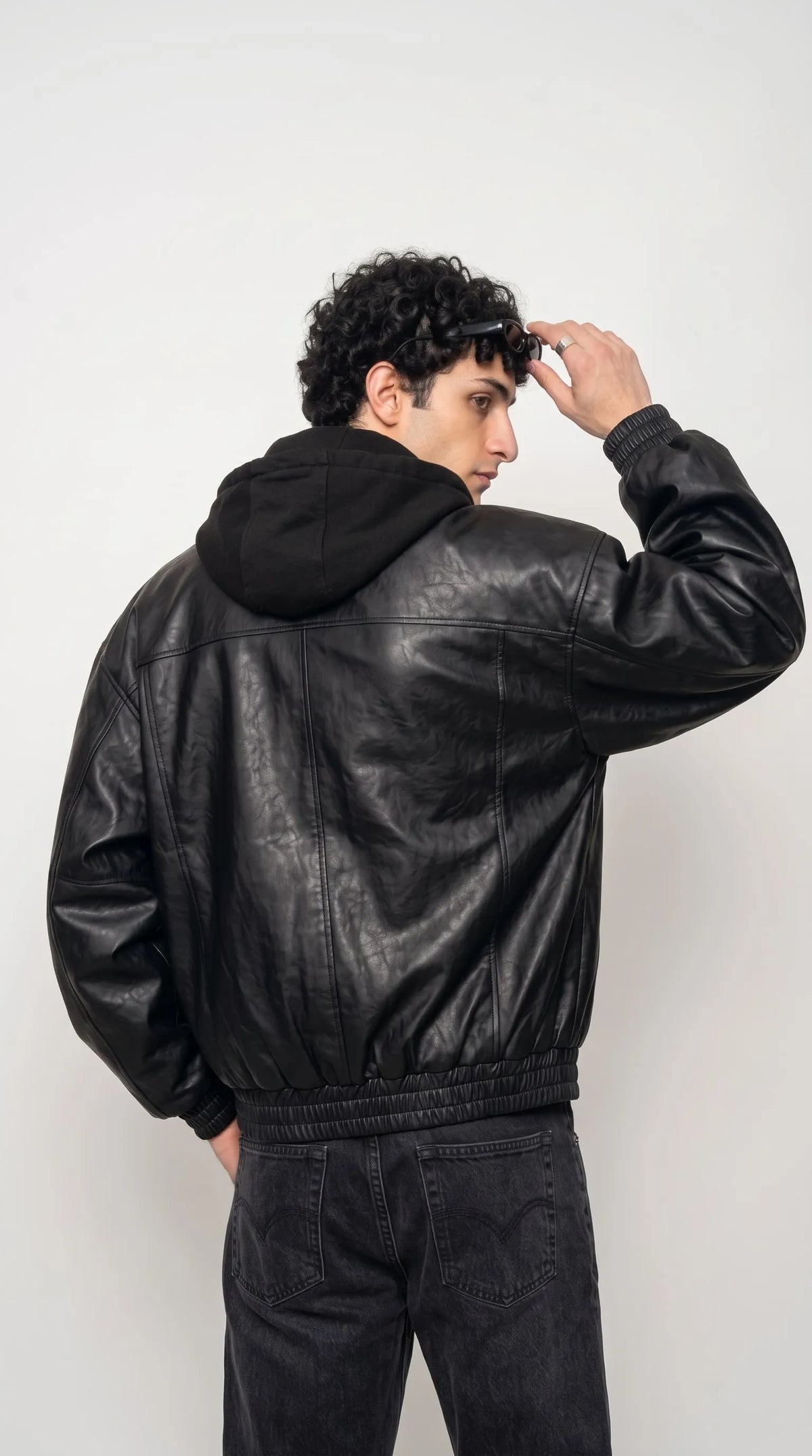 Black leather jacket with hood styled for a hip hop inspired street look, a versatile layering piece for a night out or casual city wear
