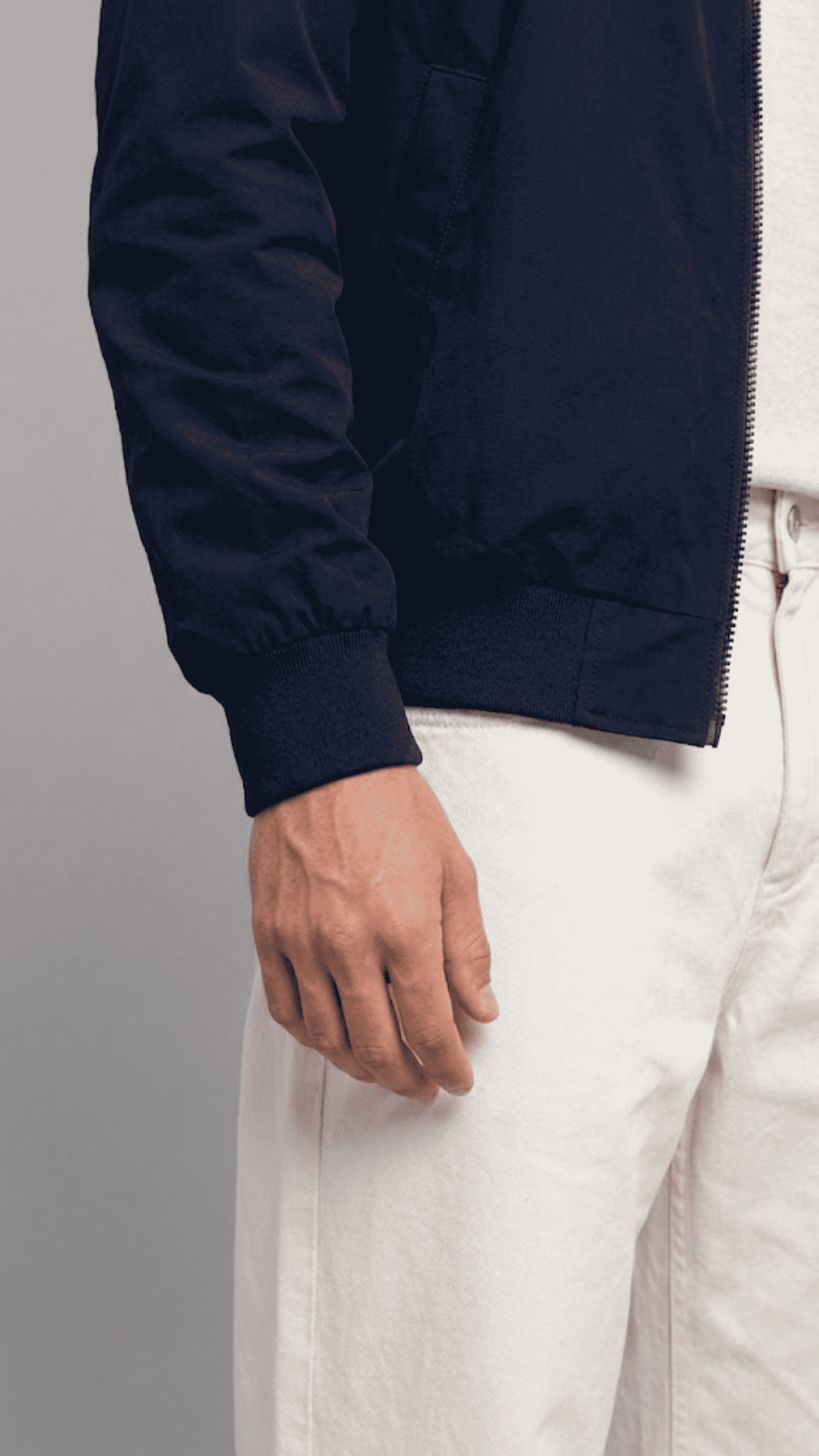 Close-up view of side welt hand pockets and smooth metal zipper slide on dark navy cotton outerwear