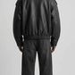 Back view displaying oversized dropped shoulder silhouette and ribbed hem on genuine black leather coat.
