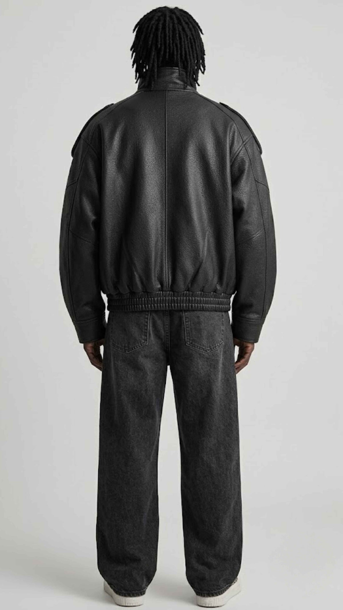 Back view displaying oversized dropped shoulder silhouette and ribbed hem on genuine black leather coat.