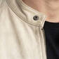 Macro detailed focus capture showing the smooth premium ivory grain texture and sleek silver hardware accents on the off-white leather jacket.