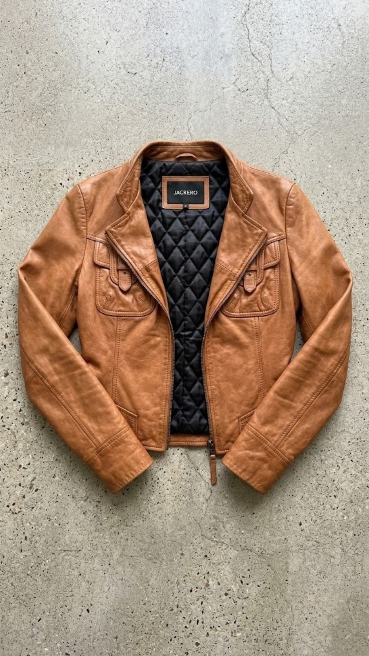 Jackero jacket flat lay presentation featuring the contemporary chestnut brown leather rider jacket neatly laid out on a neutral studio backdrop.