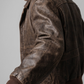 Macro detailed focus capture capturing the authentic distressed markings and rich textured patina of the rustic brown leather jacket.