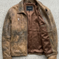 Retro fashion aesthetic featuring a premium light brown distressed leather outerwear on a light grey background.