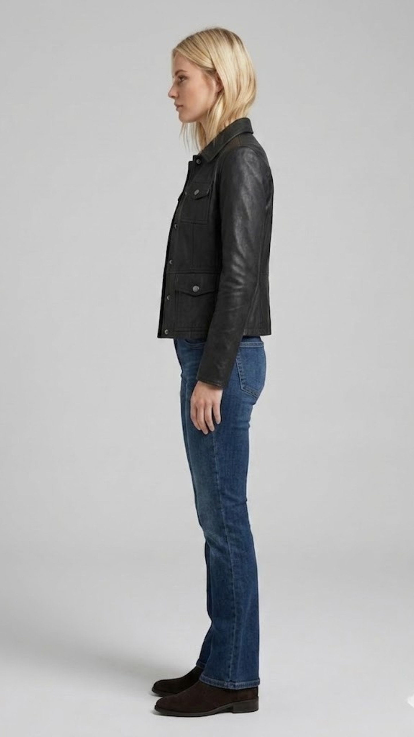 Side angle profile view highlighting the classic adjustable button waist tabs and clean shirt-style cuffs of the black leather outerwear.