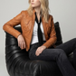 Premium women's style lookbook editorial showcasing a layered smart casual wardrobe aesthetic anchored by a luxury light brown leather motorcycle coat.