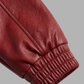 Close-up of a red leather sleeve with a gathered elastic cuff, shown against a solid gray background.