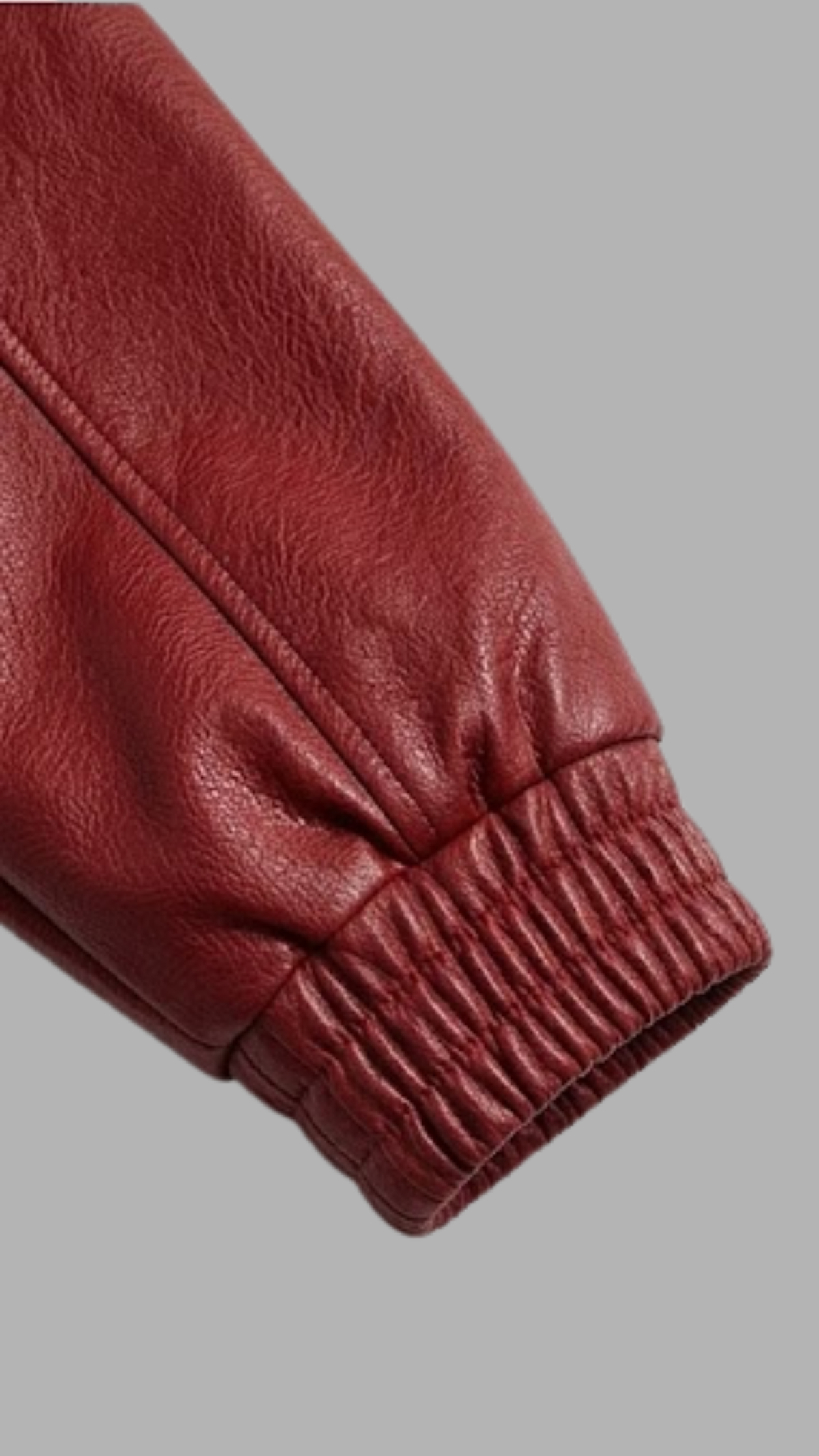 Close-up of a red leather sleeve with a gathered elastic cuff, shown against a solid gray background.