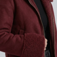 Detailed macro close-up of the plush cream-colored shearling collar and genuine dark maroon suede leather texture on the aviator jacket lapel.