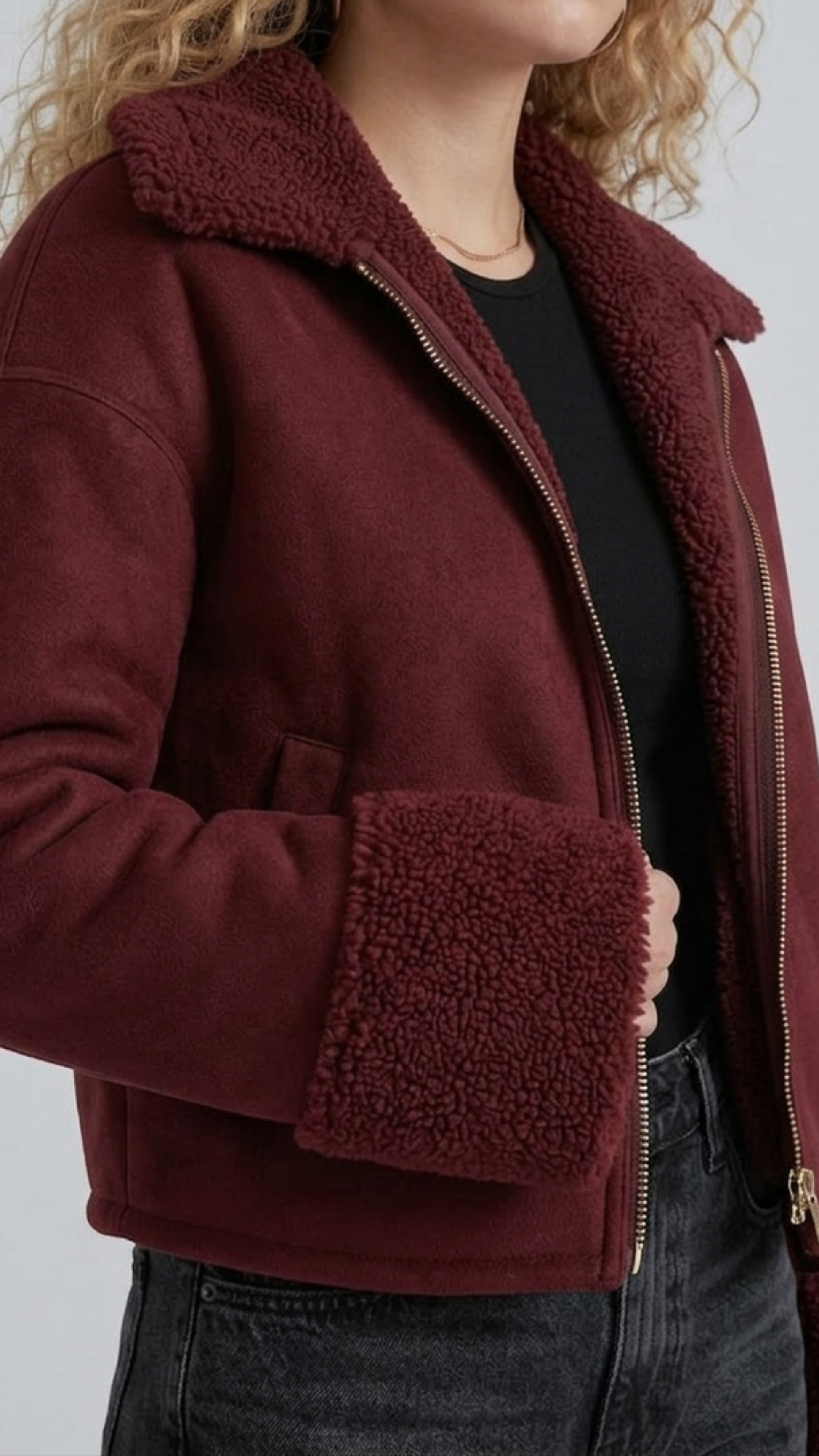 Detailed macro close-up of the plush cream-colored shearling collar and genuine dark maroon suede leather texture on the aviator jacket lapel.