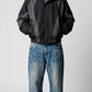 Front view of model wearing an oversized Y2K black and dark grey nylon jacket with full zip front and stand collar
