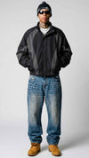 Front view of model wearing an oversized Y2K black and dark grey nylon jacket with full zip front and stand collar