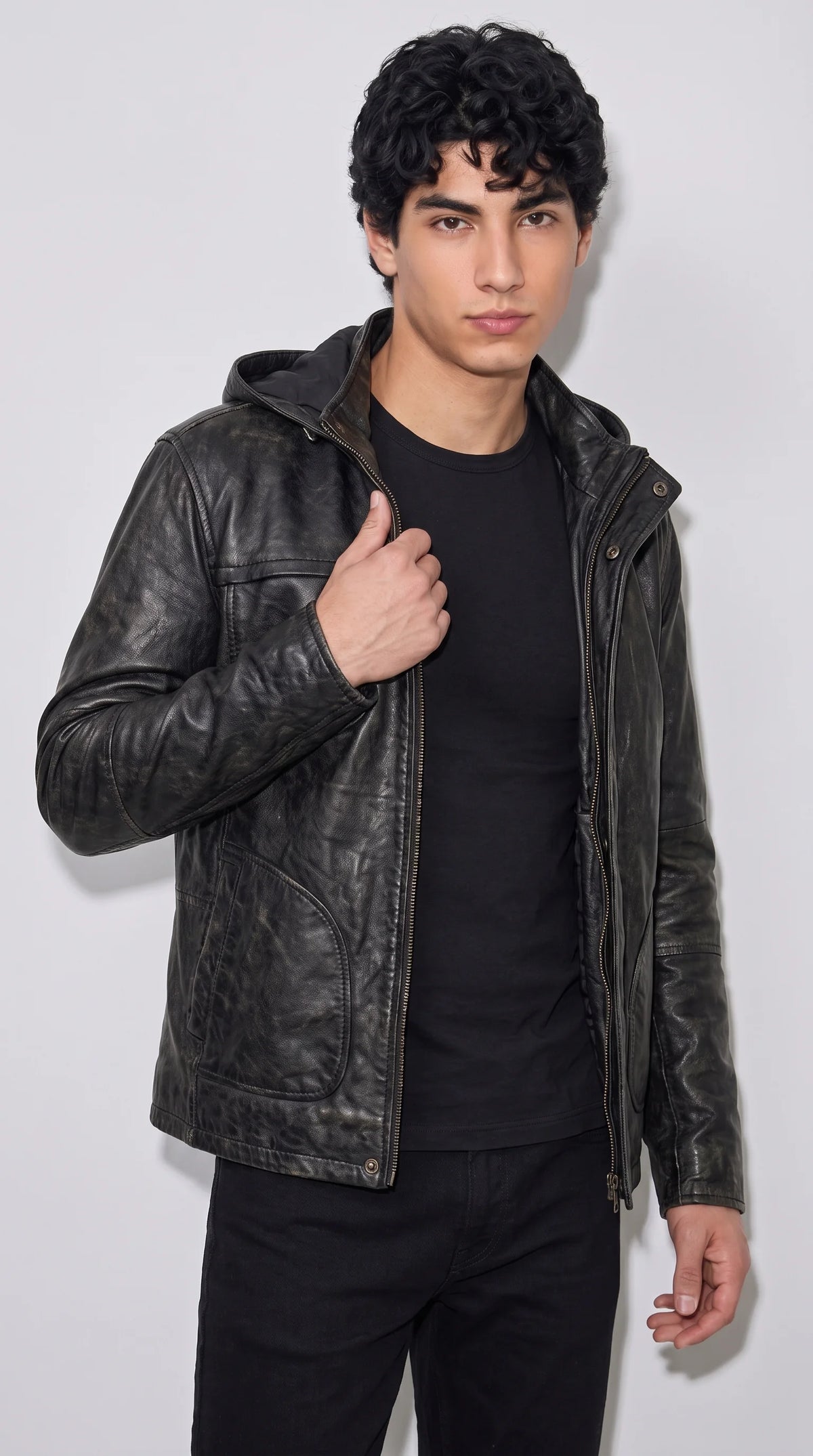 Men’s black genuine leather hooded jacket with a rugged vintage-textured finish, full front zip and modern urban streetwear styling, paired with a black T-shirt for a sleek all-black casual outfit.