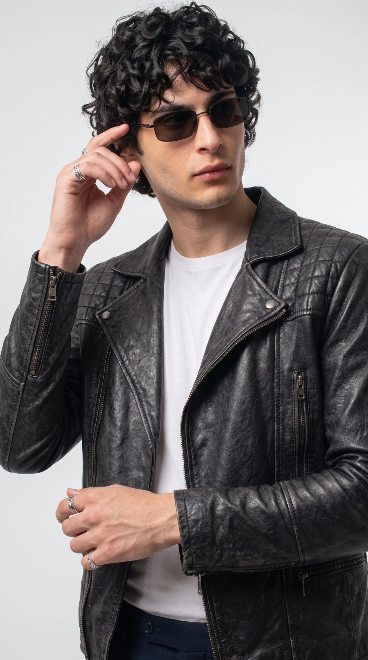 Black grained leather biker jacket showcasing diamond-quilted shoulders, snap-button lapels, polished silver zipper teeth and vertical zippered chest pockets, combining rugged motorcycle heritage with a refined contemporary designer aesthetic.