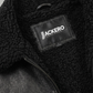 Black leather jacket with black shearling with a visible brand label on a gray background
