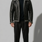 Man wearing a black leather jacket with gray fur lining on a plain background