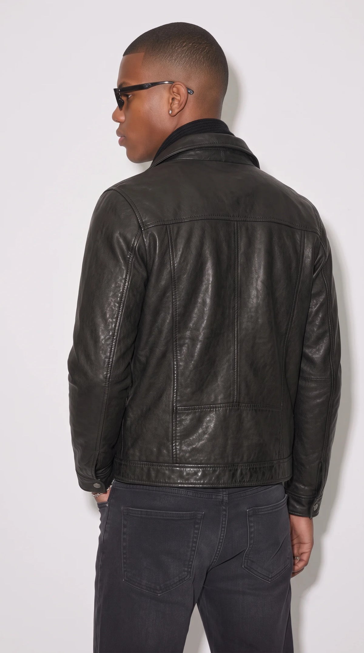Black leather workwear trucker jacket featuring two symmetrical chest pockets with secure snap-button flaps, polished metallic fasteners, a structured pointed collar and neat tonal stitching for a classic utility-inspired fashion statement.