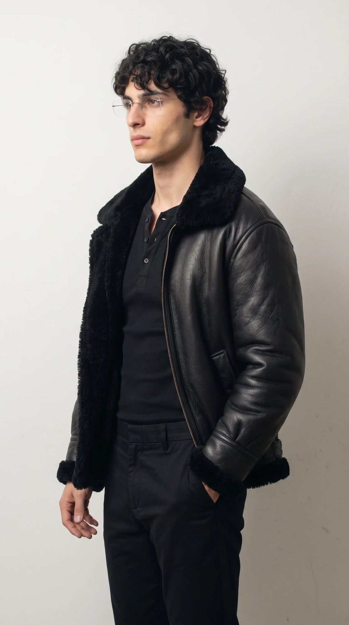Black leather aviator jacket with a generously lined fold-down collar, plush shearling borders, a full-length metal front zipper and softly gathered sleeves, layered over a black henley for elevated cold-weather streetwear.