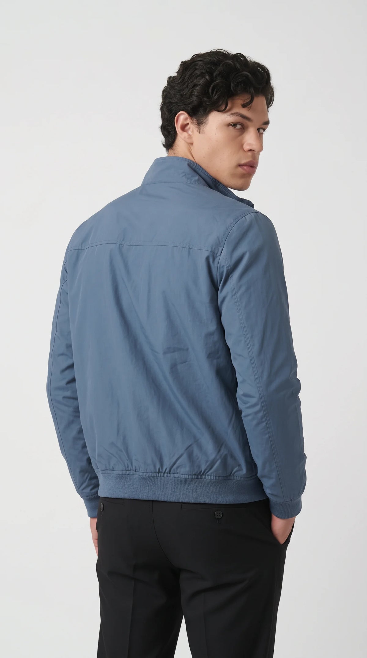 Contemporary cyan-blue bomber jacket with a clean rear shoulder yoke, carefully finished sleeve seams and matching rib-knit waistband that maintains its classic bomber shape. The softly structured silhouette and understated blue-grey finish make this silk-cotton outerwear piece easy to combine with black denim, neutral trousers and simple layers for polished everyday menswear.