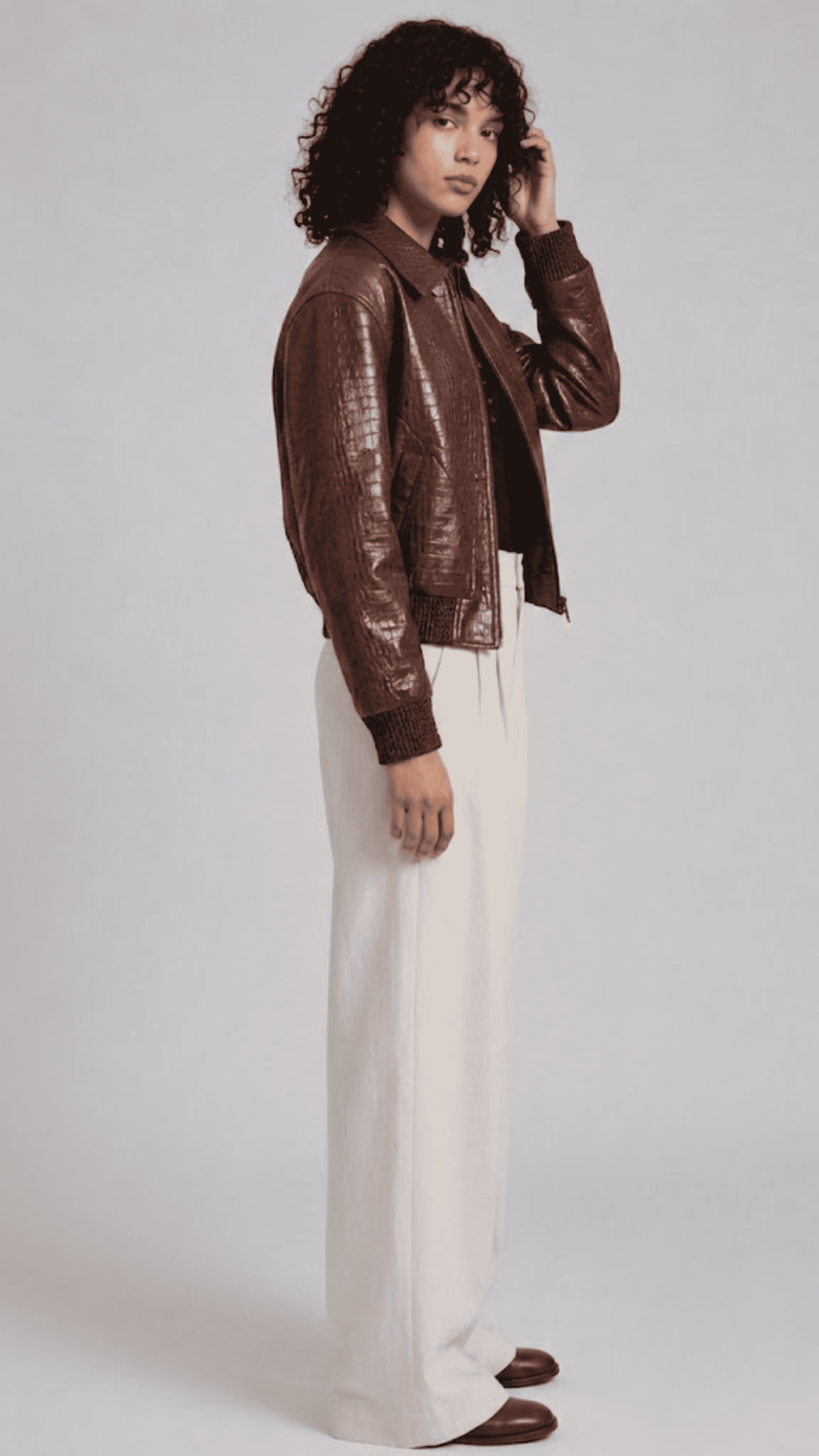 Dark brown leather jacket with crocodile texture detailing, front zip closure, and dark brown ribbed cuffs.