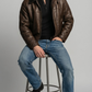 A stylish and rugged dark brown leather winter jacket with black shearling details, ideal for cold weather fashion.