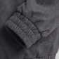 Close-up of a dark gray suede jacket with a focus on the sleeve and waistband.