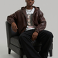 Men's slim fit genuine burgundy leather bomber jacket displaying clean stitching details, side pockets, and integrated casual grey hoodie fabric.