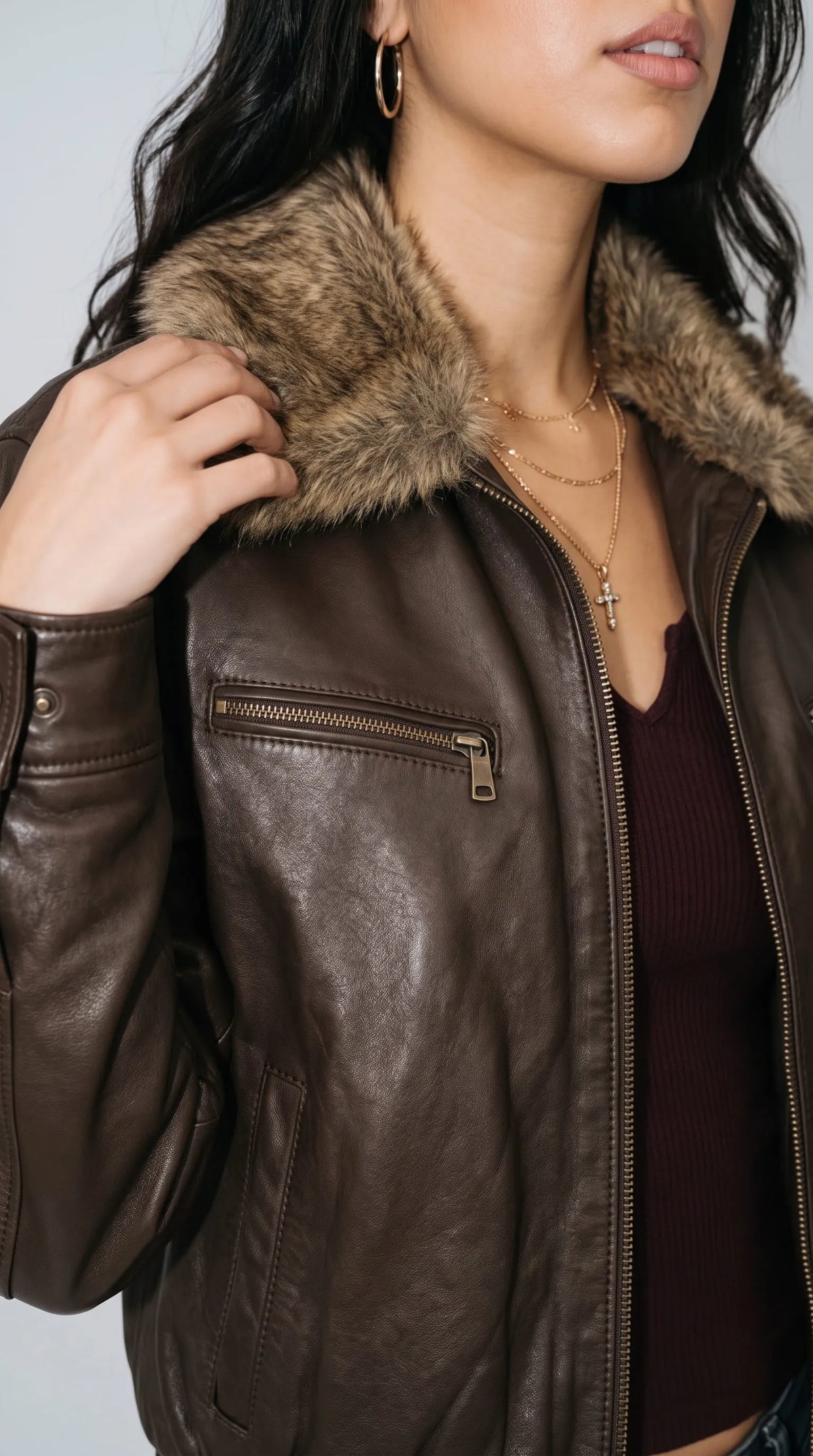 Close-up of a dark chocolate genuine leather bomber jacket highlighting its thick taupe-brown faux-fur collar, horizontal chest pocket with metallic zipper, full-length front zip and naturally distressed leather grain. The contrast between the plush collar and the softly creased brown leather adds depth and texture, showcasing the jacket’s rugged aviator character and distinctive vintage-inspired hardware.