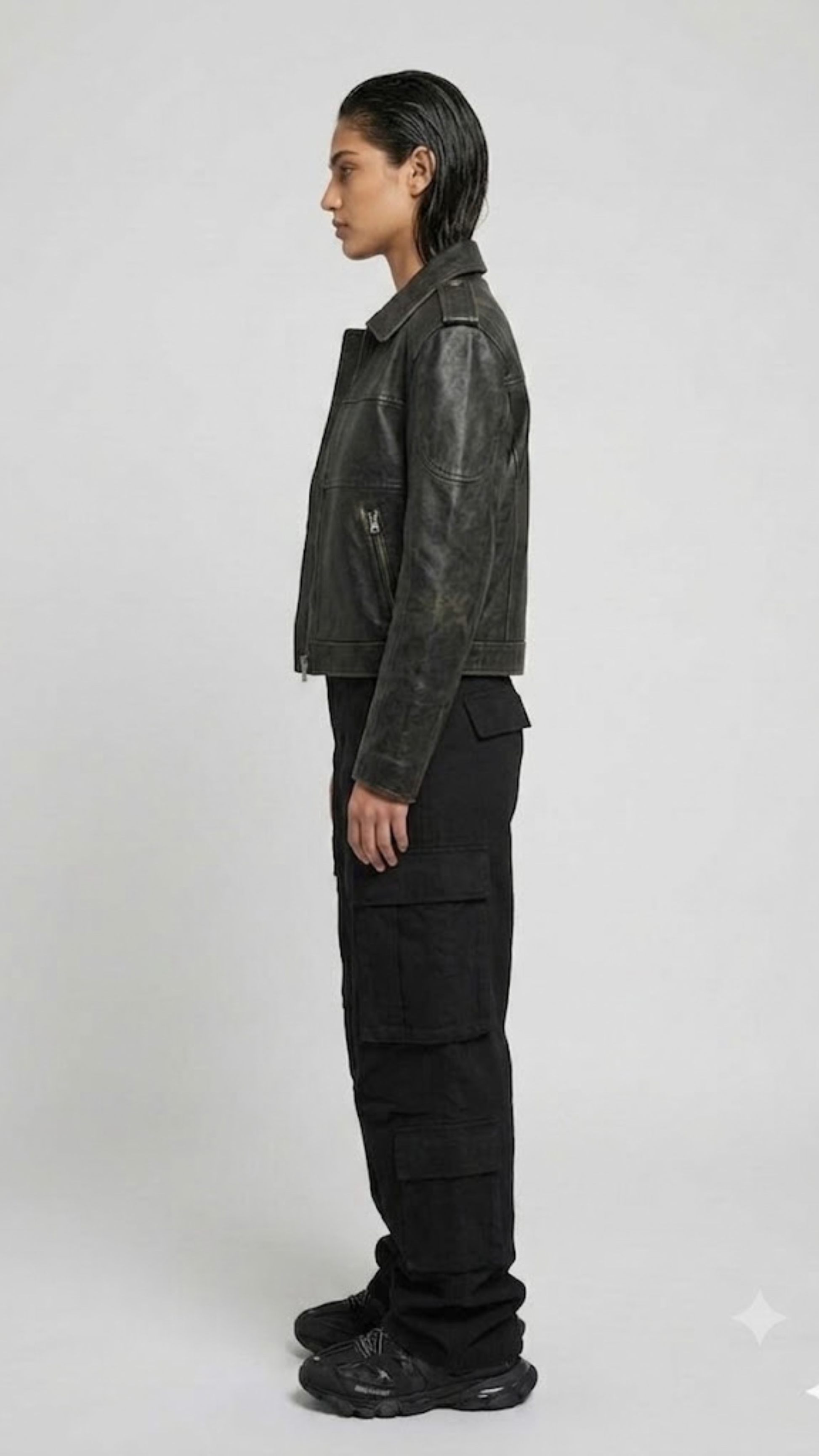 Person wearing a dark black jacket and black pants on a white background