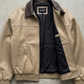 Beige jacket with black lining on a gray concrete surface
